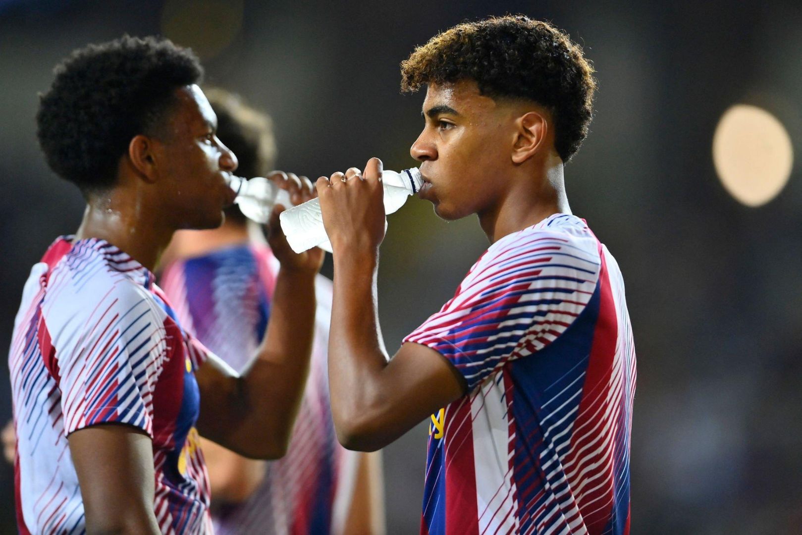 Barcelona's Spanish defender #03 Alejandro Balde (L) and Barcelona's Spanish forward #27 Lamine Yamal drink before the Spanish Liga football match between FC Barcelona and Sevilla FC at the Estadi Olimpic Lluis Companys in Barcelona on September 29, 2023.