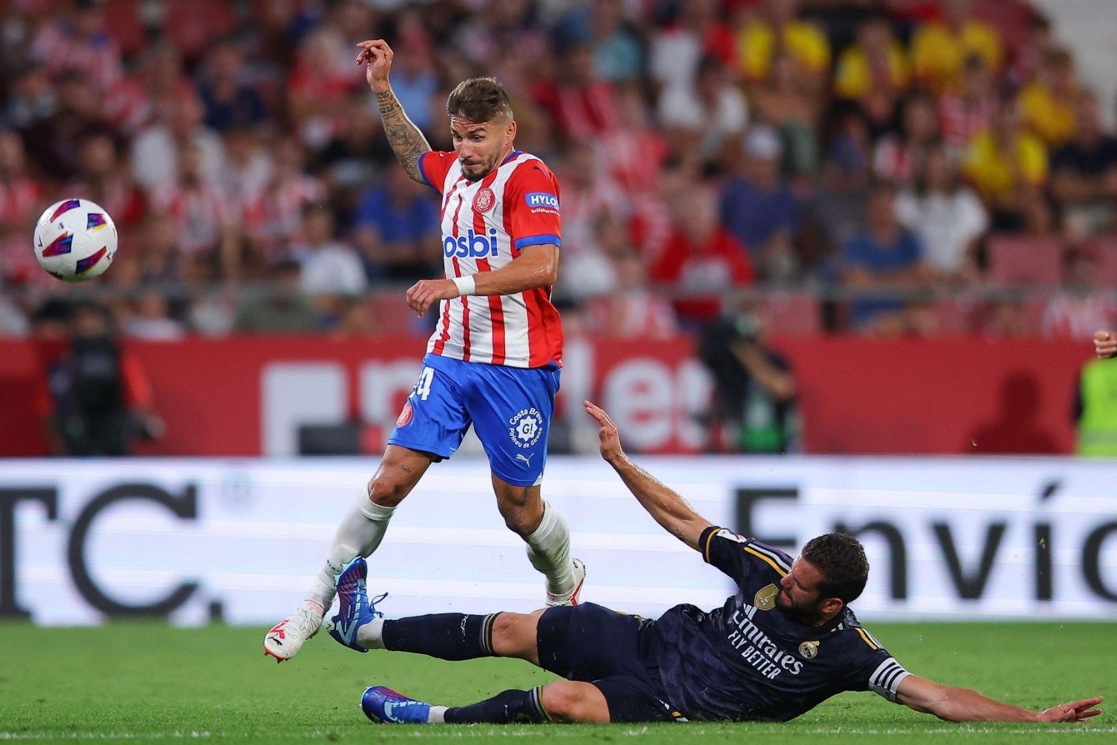Portu of Girona FC is tackled by Nacho Fernandez of Real Madrid during the LaLiga EA Sports match between Girona FC and Real Madrid CF at Montilivi Stadium on September 30, 2023 in Girona, Spain