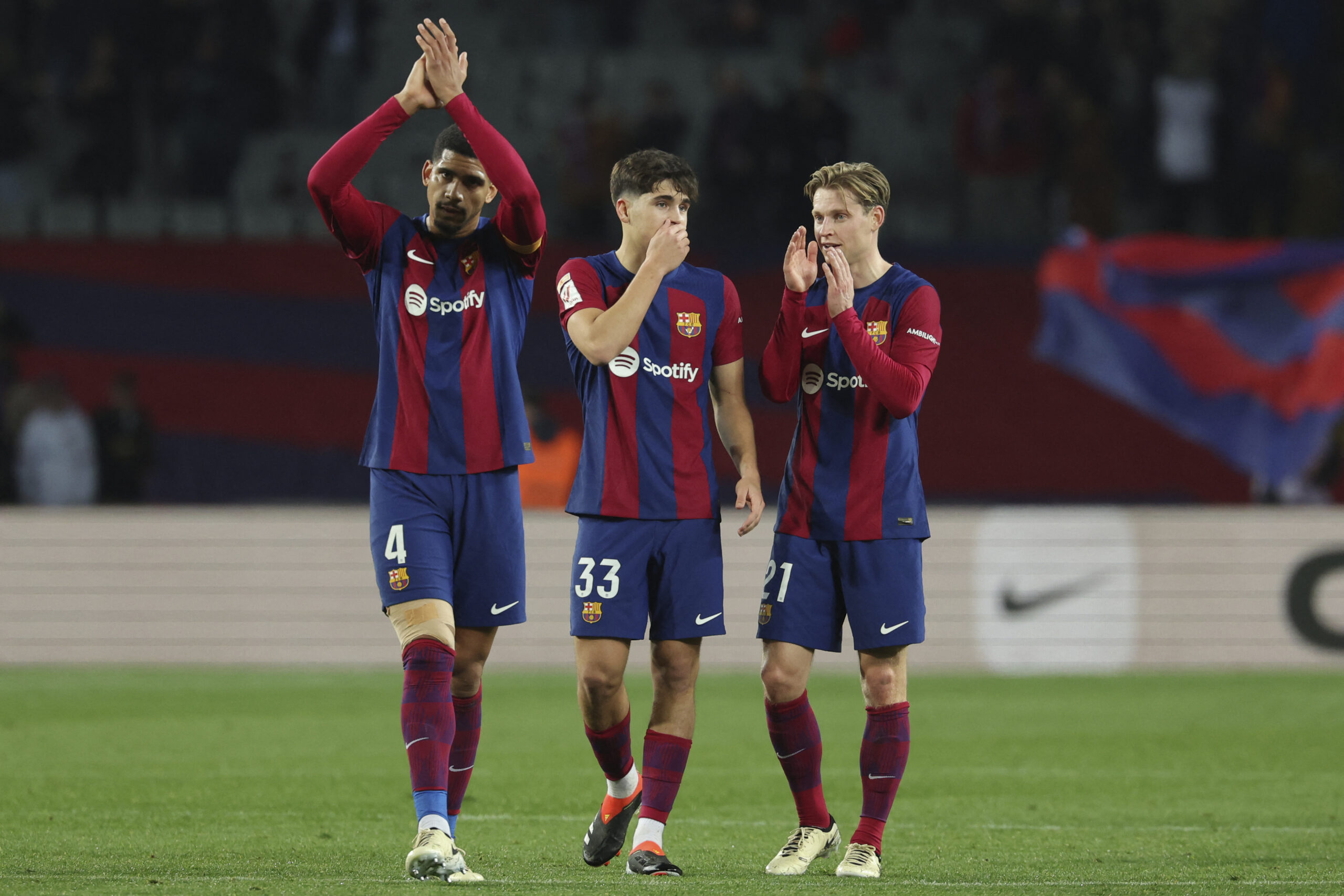 Barcelona's Uruguayan defender #04 Ronald Araujo (L) claps, next to Barcelona's Spanish defender #33 Pau Cubarsi and Barcelona's Dutch midfielder #21 Frenkie de Jong (R) at the end of during the Spanish league football match between FC Barcelona and CA Osasuna at the Estadi Olimpic Lluis Companys in Barcelona on January 31, 2024.
