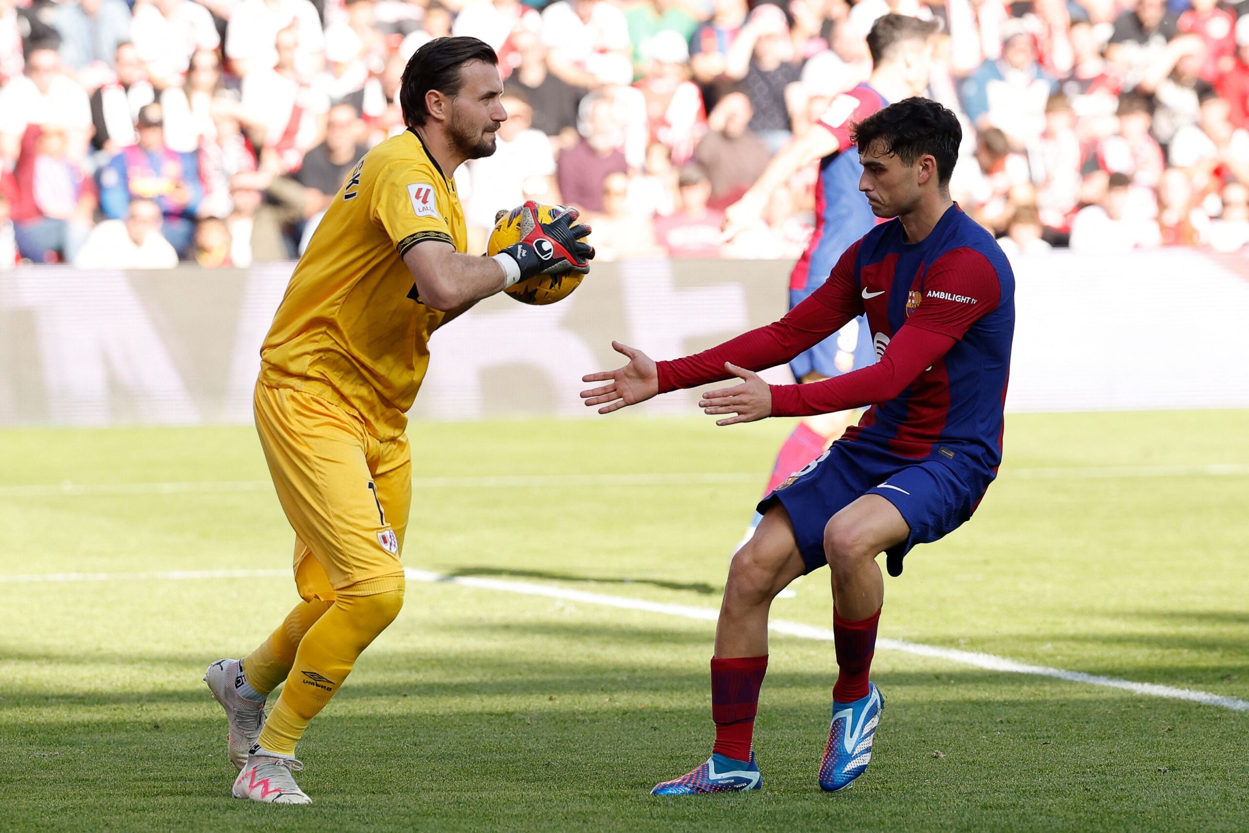 Rayo Vallecano's North Macedonian goalkeeper #01 Stole Dimitrievski holds the ball next to Barcelona's Spanish midfielder #08 Pedri during the Spanish league football match between Rayo Vallecano de Madrid and FC Barcelona on November 25, 2023.