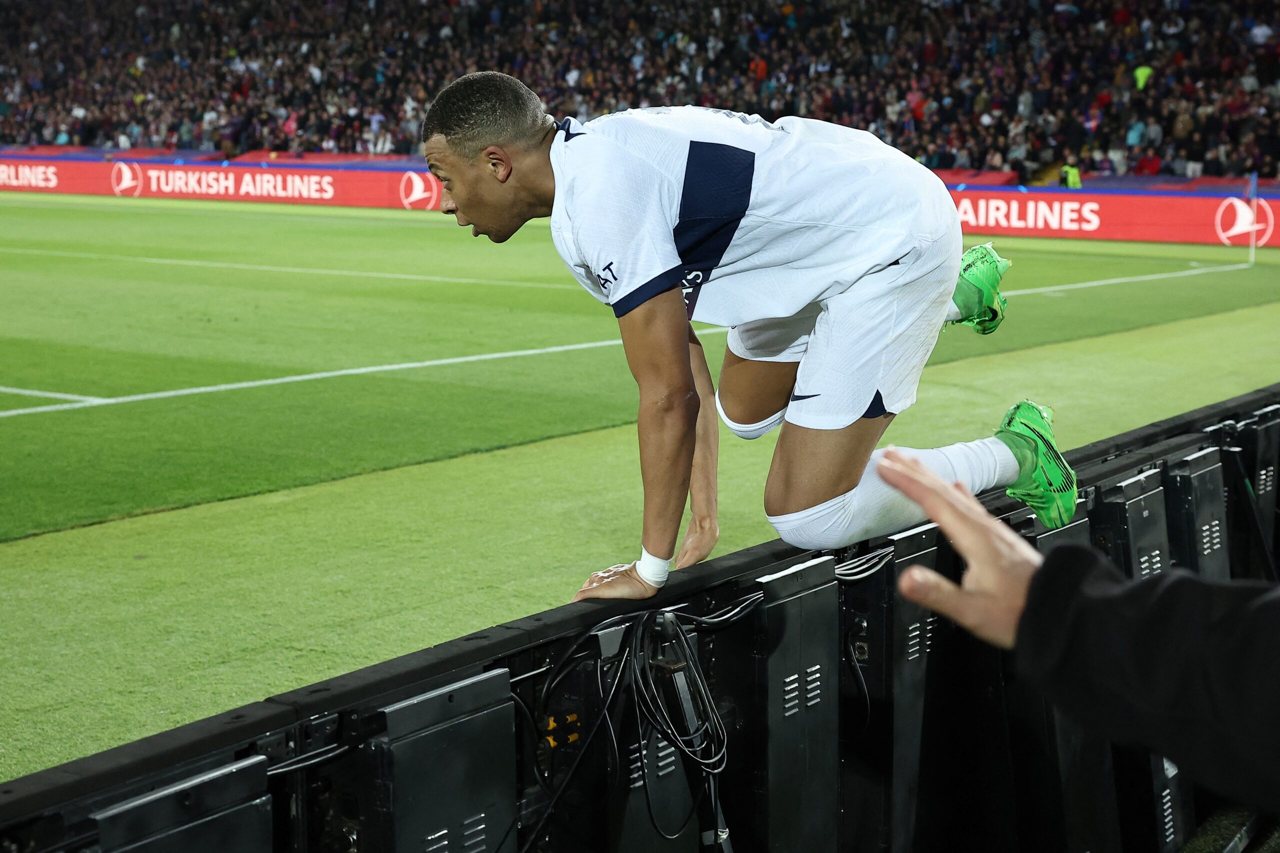 Paris Saint-Germain's French forward #07 Kylian Mbappe jumps the fence as he celebrates scoring his second goal and his team's fourth goal during the UEFA Champions League quarter-final second leg football match between FC Barcelona and Paris SG at the Estadi Olimpic Lluis Companys in Barcelona on April 16, 2024.
