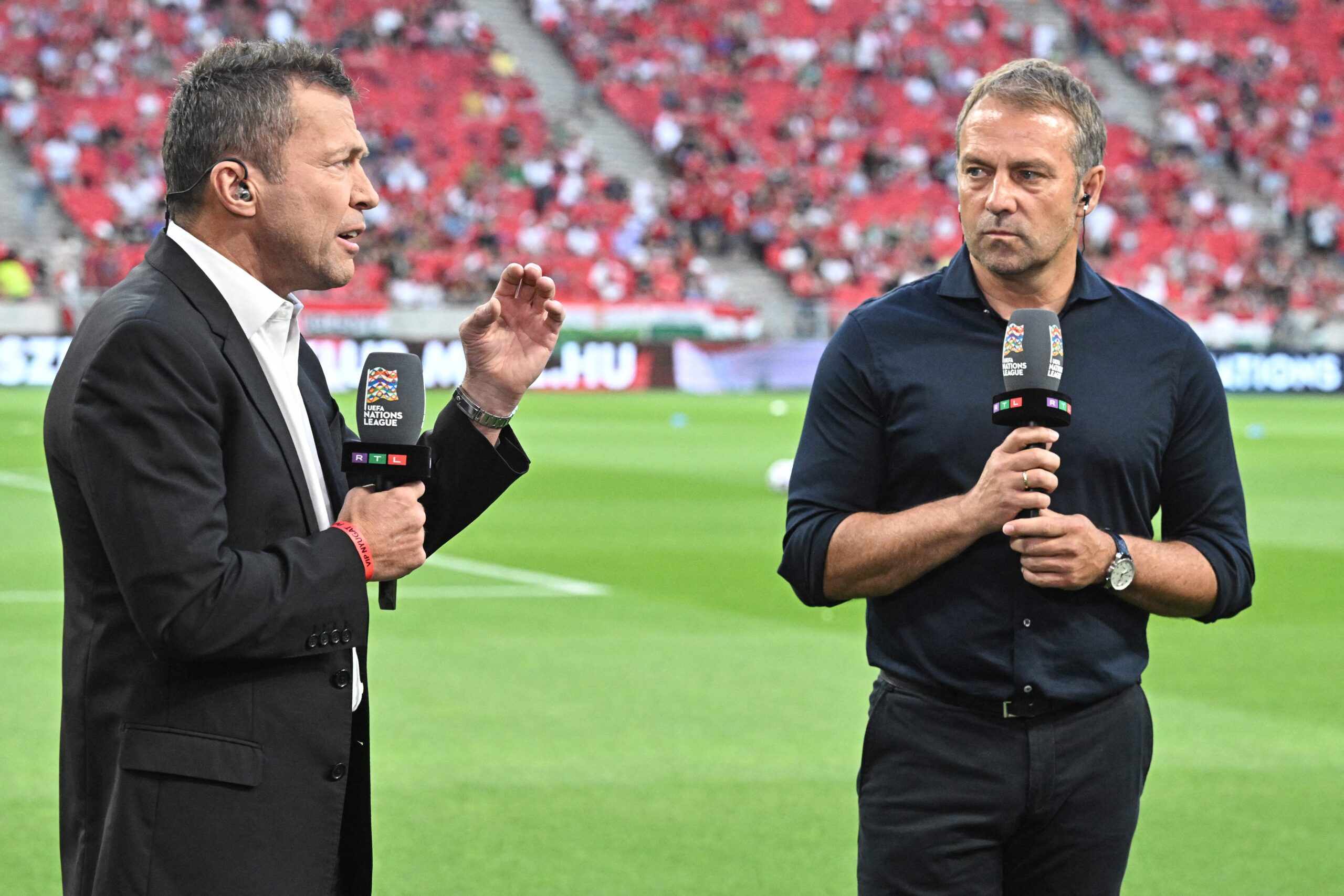 Germany's coach Hans-Dieter Flick (R) speaks with former Germany player Lothar Matthaus for television prior to the UEFA Nations League football match Hungary v Germany in Budapest on June 11, 2022.