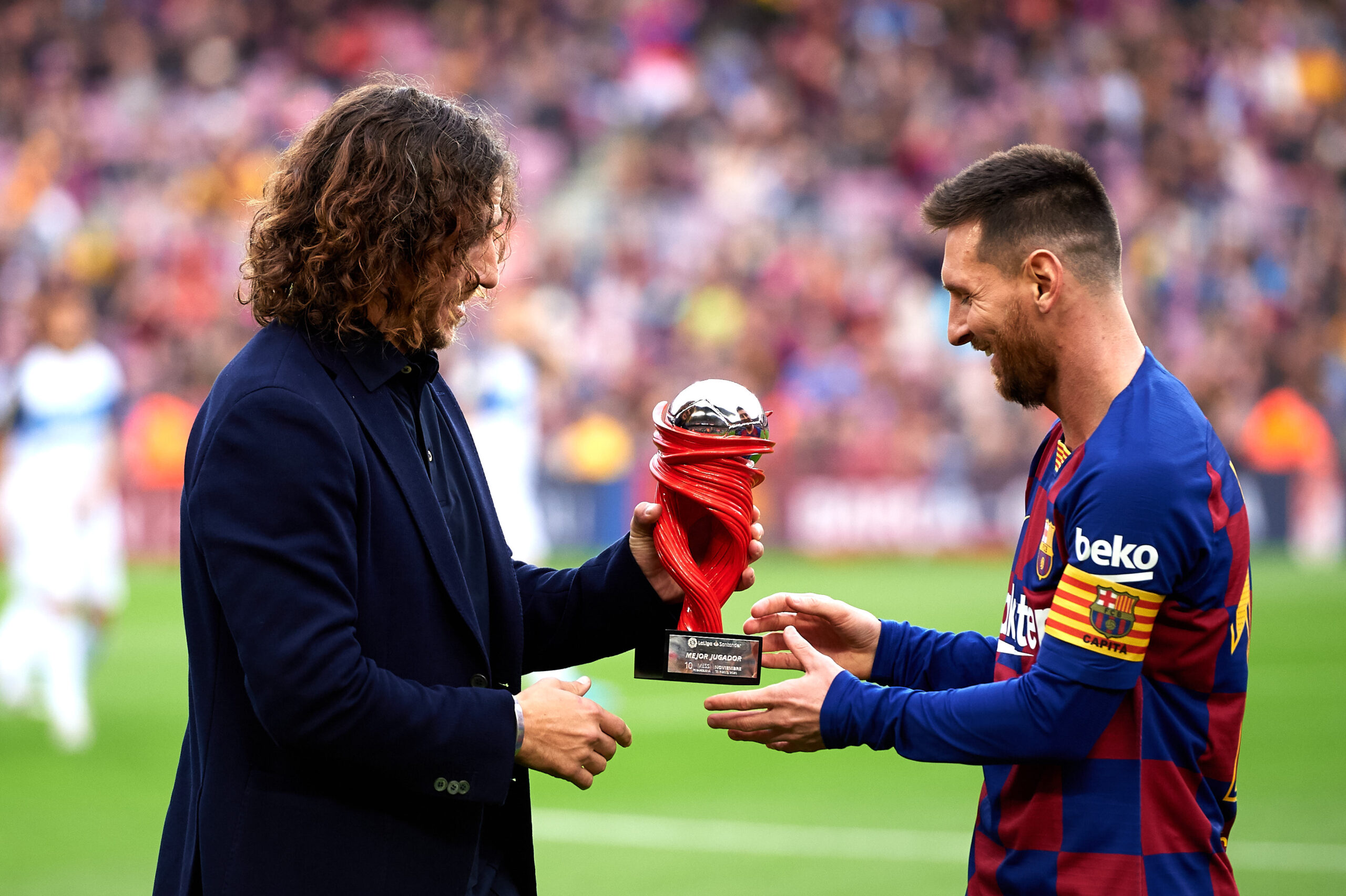 BARCELONA, SPAIN - DECEMBER 21: Lionel Messi of FC Barcelona receives the trophy as best player of November in the Spanish La Liga from Carles Puyol before the La Liga match between FC Barcelona and Deportivo Alaves at Camp Nou on December 21, 2019 in Barcelona, Spain.