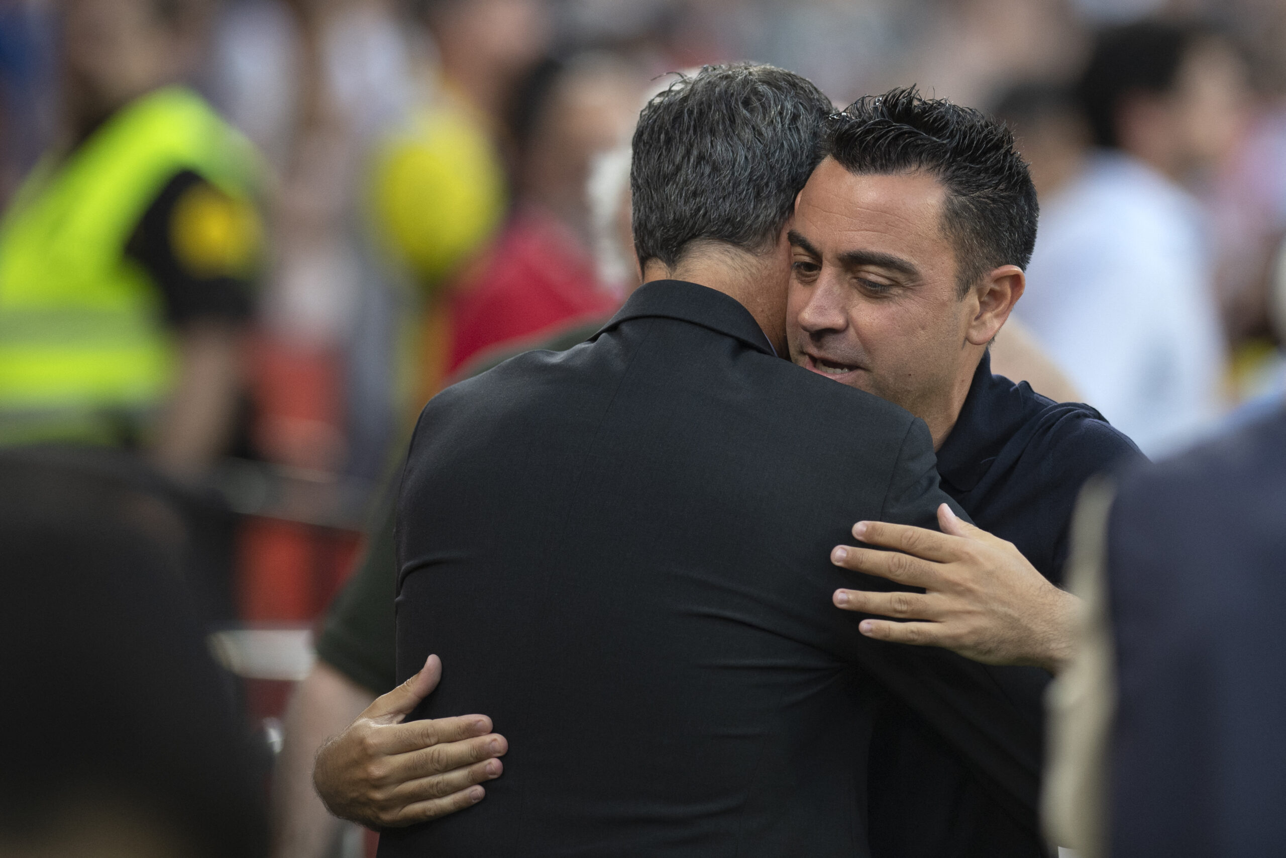 Barcelona's Spanish coach Xavi Hernandez (R) hugs Sevilla's Spanish head coach Quique Sanchez Flores prior to the Spanish league football match between Sevilla FC and FC Barcelona at the Ramon Sanchez Pizjuan stadium in Seville on May 26, 2024.