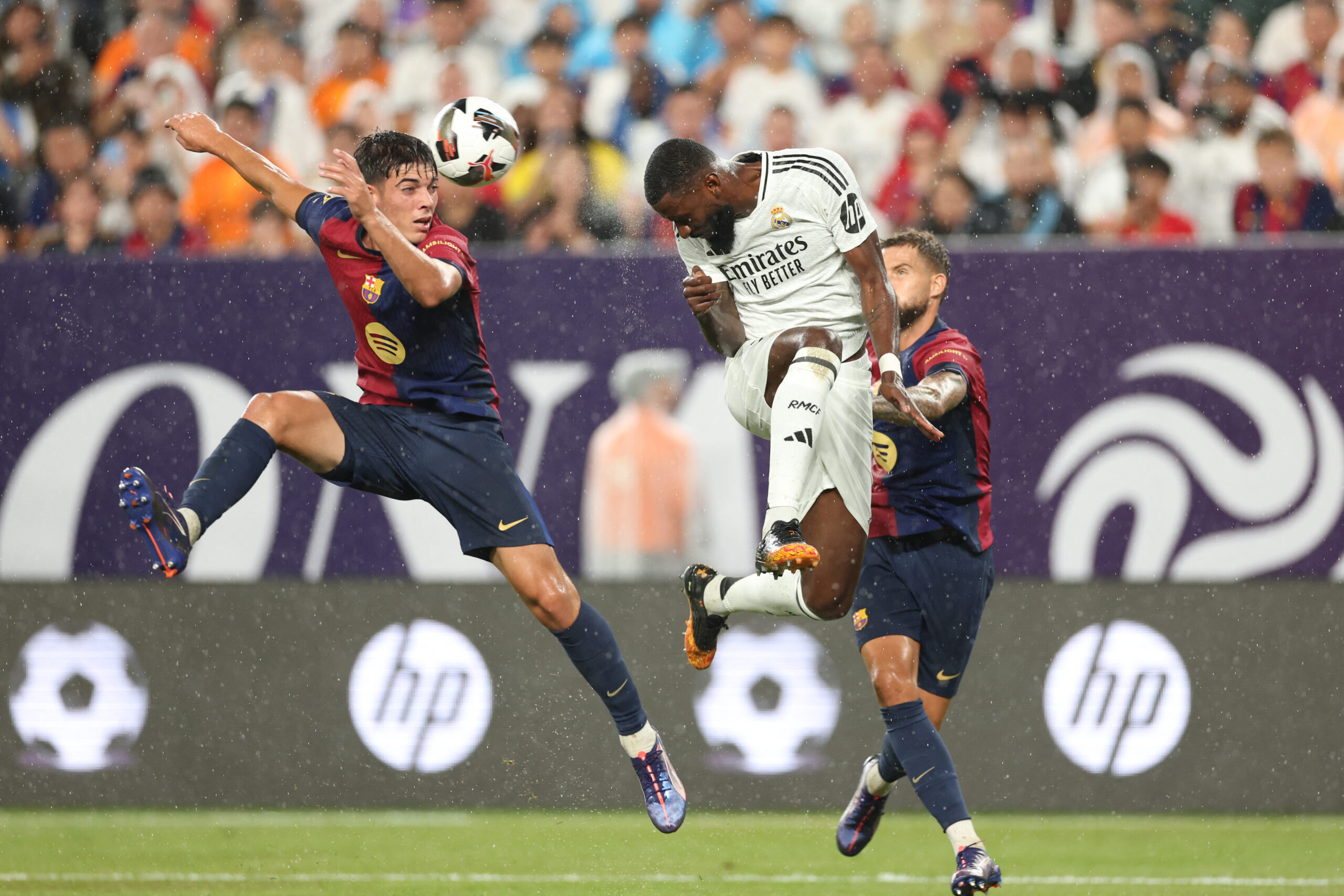 Barcelona's Spanish defender #12 Alex Valle (L) vies for the ball with Real Madrid's German defender #22 Antonio Rudiger (C) during the pre-season club friendly football match between Real Madrid and Barcelona at MetLife Stadium in East Rutherford, New Jersey, August 3, 2024.