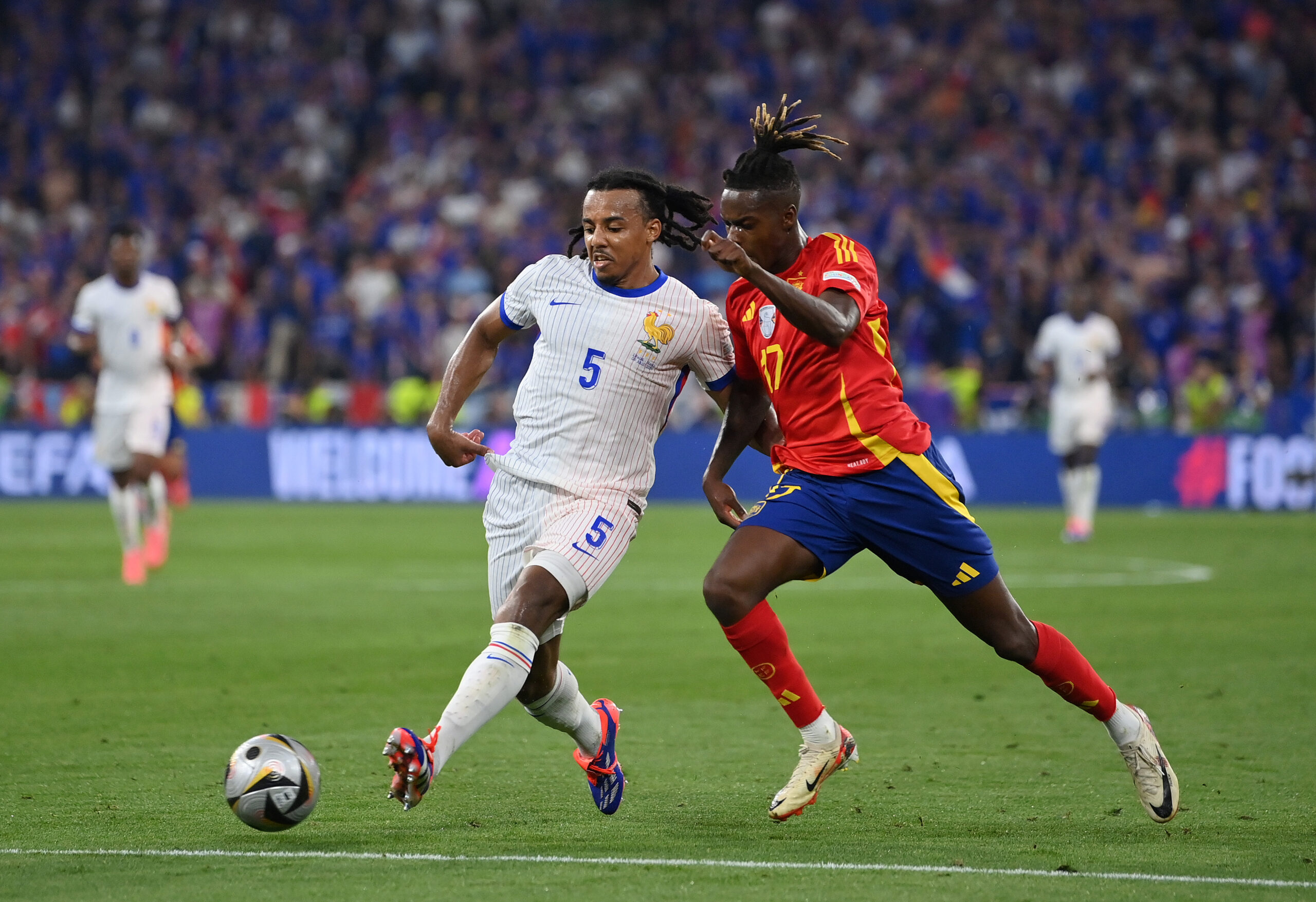 MUNICH, GERMANY - JULY 09: Jules Kounde of France passes the ball whilst under pressure from Nico Williams of Spain during the UEFA EURO 2024 Semi-Final match between Spain and France at Munich Football Arena on July 09, 2024 in Munich, Germany.