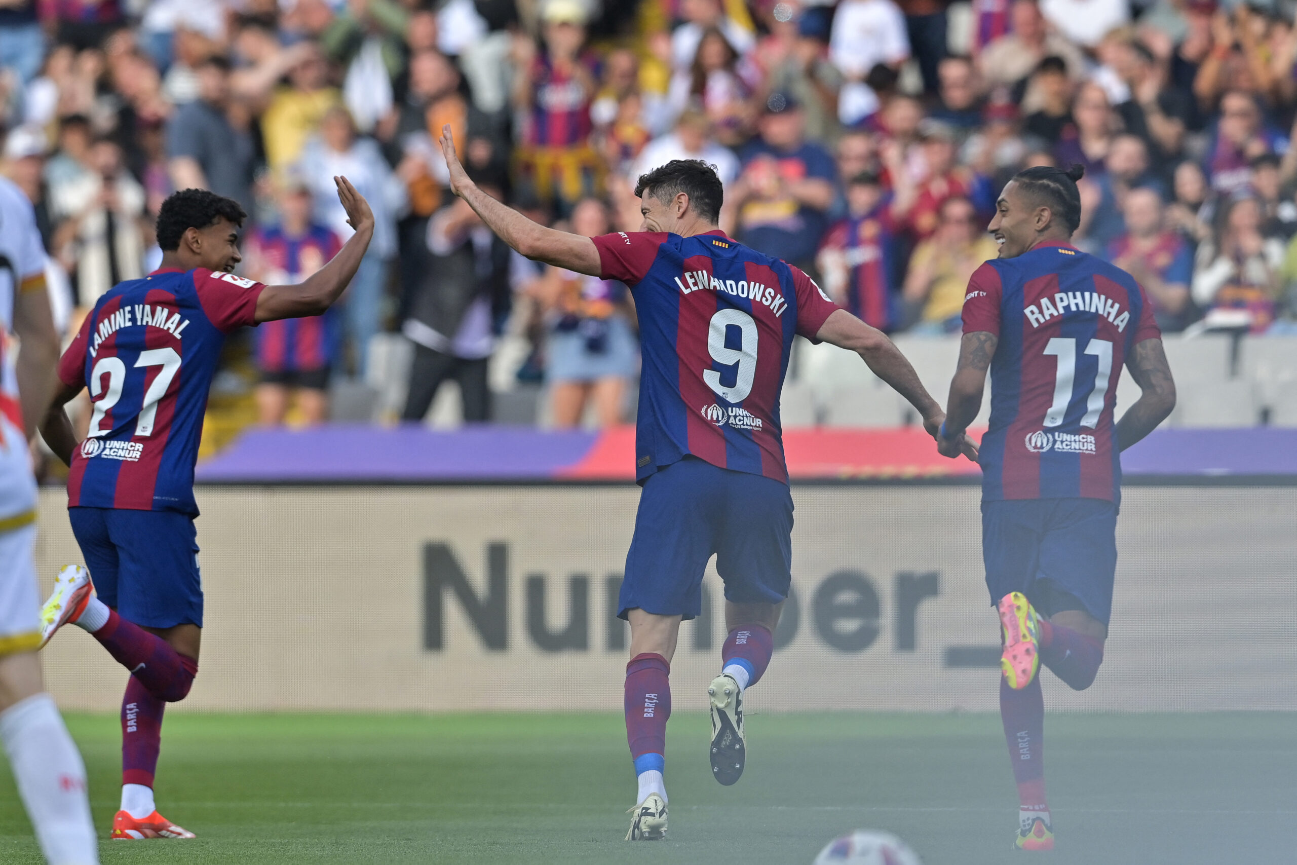 Barcelona's Polish forward #09 Robert Lewandowski celebrates with Barcelona's Spanish forward #27 Lamine Yamal and Barcelona's Brazilian forward #11 Raphinha after scoring his team's first goal during the Spanish League football match between FC Barcelona and Rayo Vallecano de Madrid at the Estadi Olimpic Lluis Companys in Barcelona on May 19, 2024.