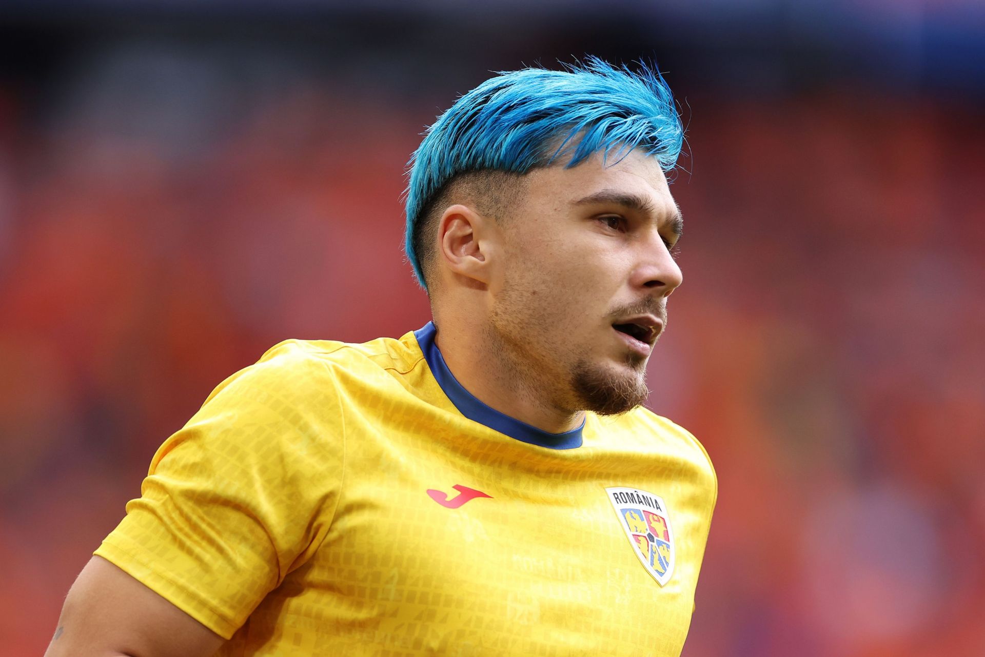 MUNICH, GERMANY - JULY 02: Andrei Ratiu of Romania looks on as he warms up, as his blue dyed hair can be seen, prior to the UEFA EURO 2024 round of 16 match between Romania and Netherlands at Munich Football Arena on July 02, 2024 in Munich, Germany.