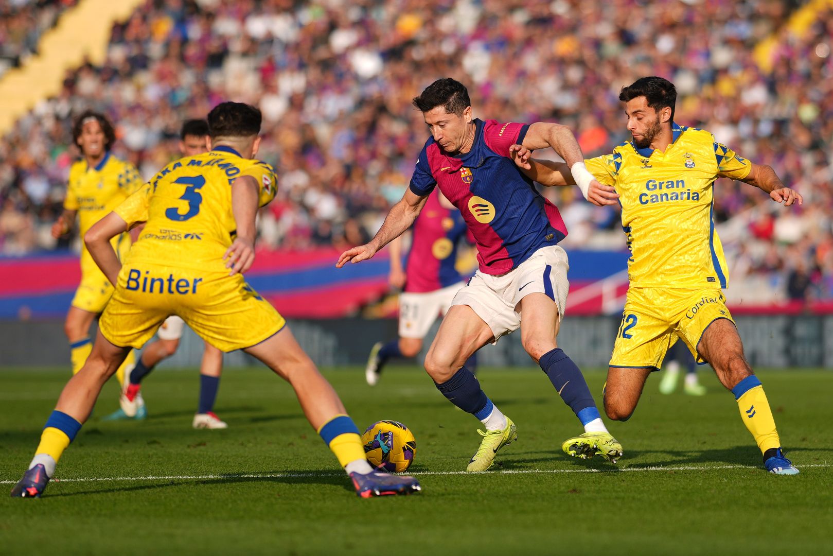 BARCELONA, SPAIN - NOVEMBER 30: Robert Lewandowski of FC Barcelona controls the ball whilst under pressure from Mika Marmol and Enzo Loiodice of UD Las Palmas during the LaLiga match between FC Barcelona and UD Las Palmas at Estadi Olimpic Lluis Companys on November 30, 2024 in Barcelona, Spain.