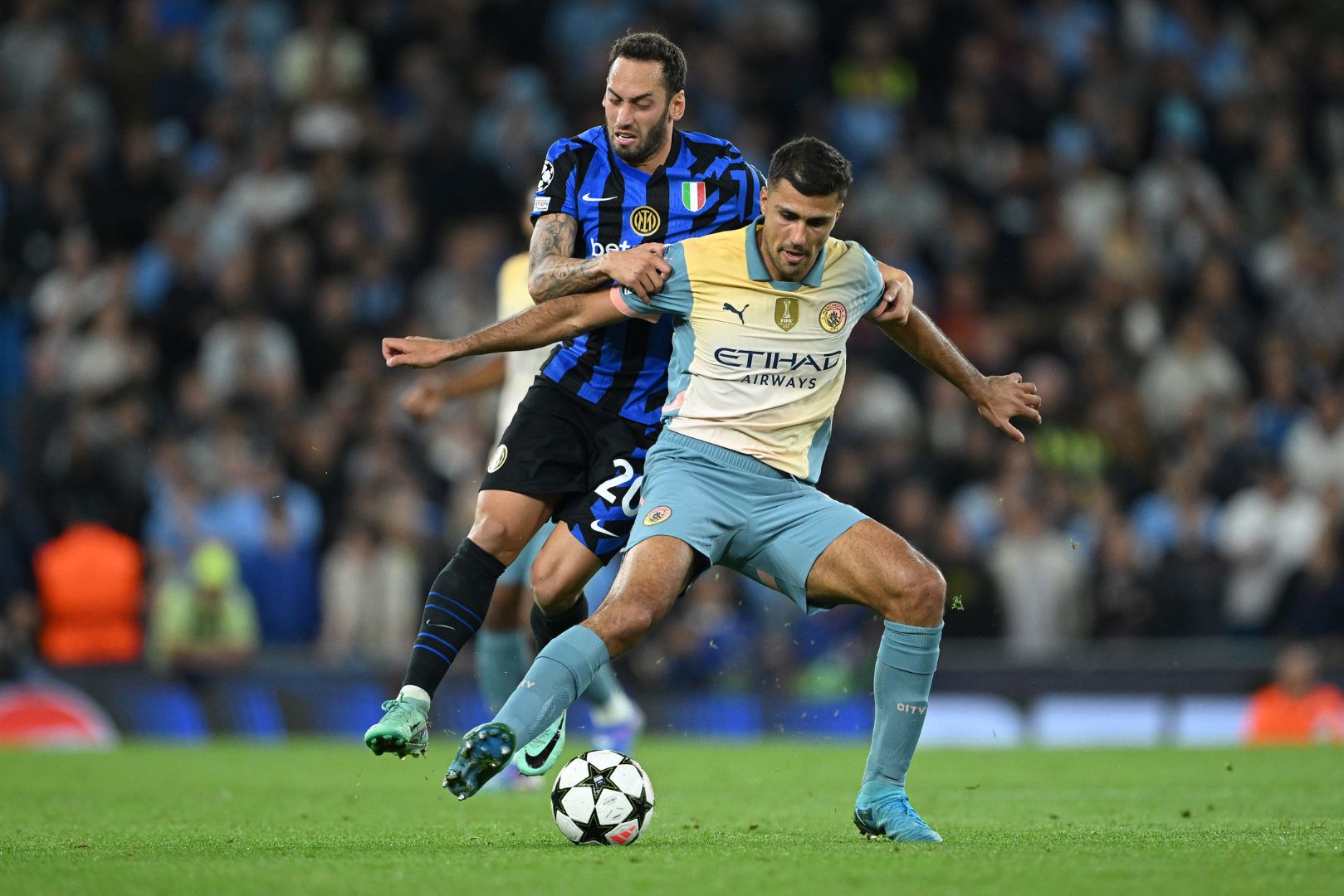 MANCHESTER, ENGLAND - SEPTEMBER 18: Rodri of Manchester City is challenged by Hakan Calhanoglu of FC Internazionale during the UEFA Champions League 2024/25 League Phase MD1 match between Manchester City and FC Internazionale Milano at City of Manchester Stadium on September 18, 2024 in Manchester, England.