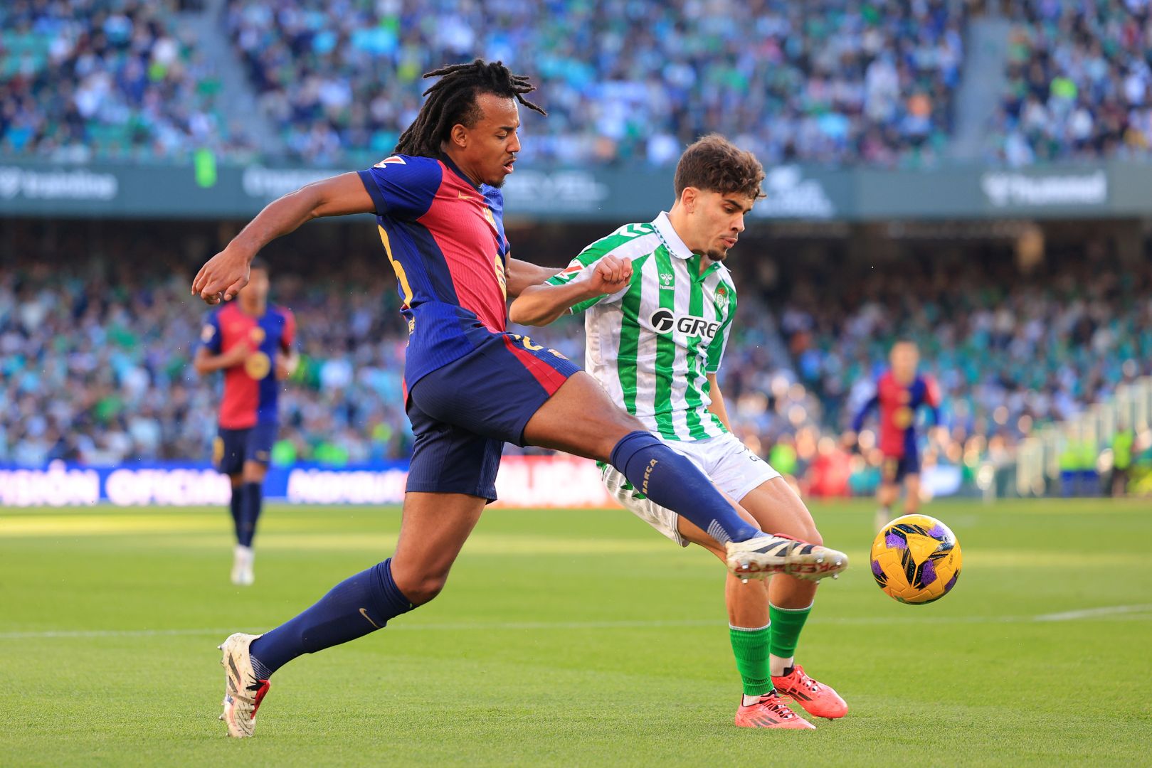 SEVILLE, SPAIN - DECEMBER 07: Jules Kounde of FC Barcelona clears the ball whilst under pressure from Abde Ezzalzouli of Real Betis during the LaLiga match between Real Betis Balompie and FC Barcelona at Estadio Benito Villamarin on December 07, 2024 in Seville, Spain.