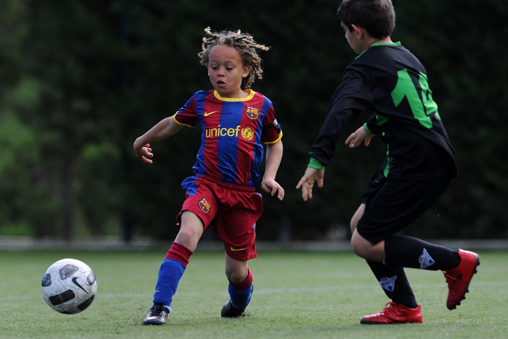 BARCELONA, SPAIN - MAY 15: Eight-year-old Barcelona youth player Xavi Simons strikes the ball besides a Llongueras youth player on one of the pitches at the Joan Camper training ground on May 15, 2011 in Barcelona, Spain. Every weekend various teams of Barcelona youth players play in matches with the hope of one day making it to the top.
