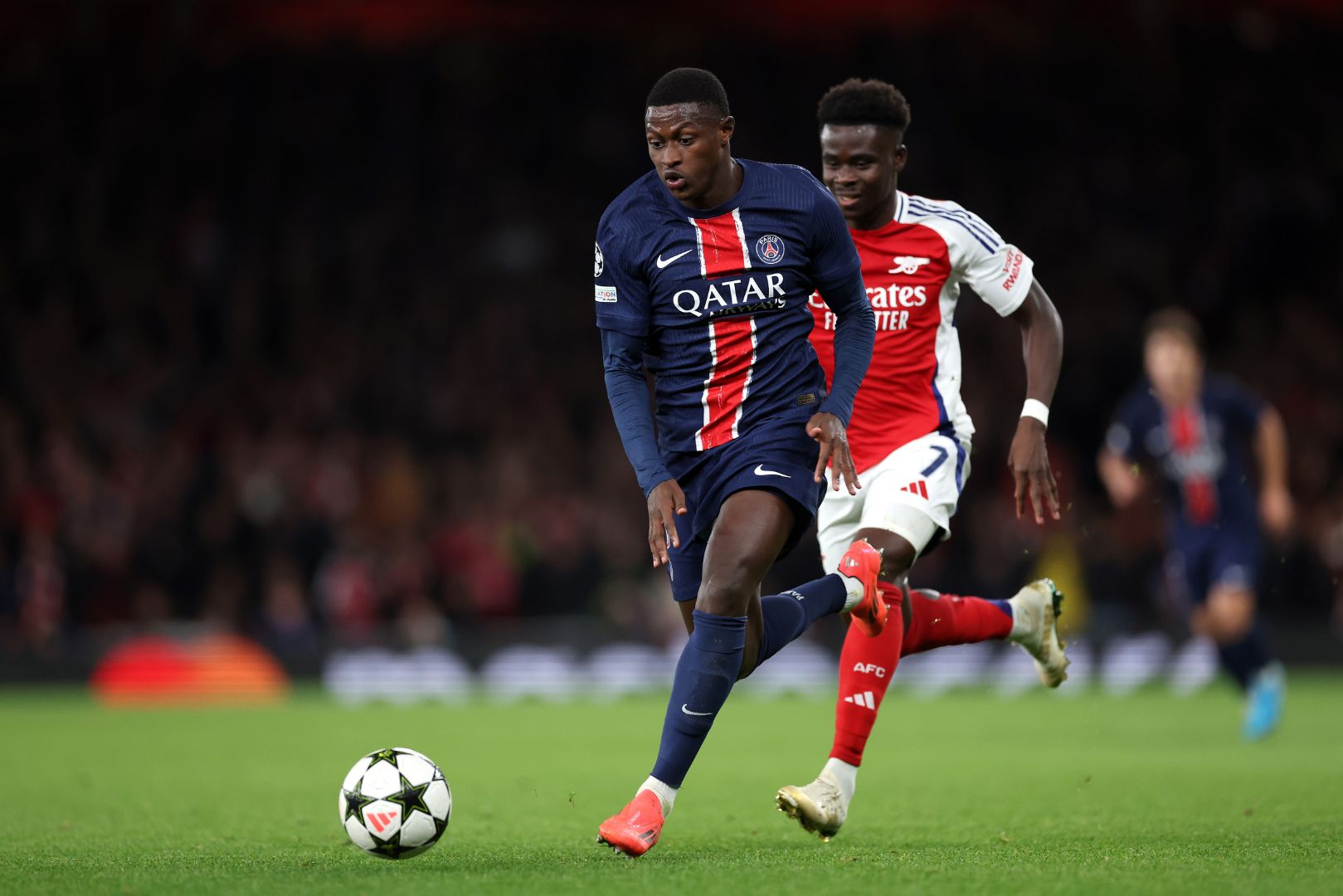 LONDON, ENGLAND - OCTOBER 01: Nuno Mendes of Paris Saint-Germain runs with the ball whilst under pressure from Bukayo Saka of Arsenal during the UEFA Champions League 2024/25 League Phase MD2 match between Arsenal FC and Paris Saint-Germain at Emirates Stadium on October 01, 2024 in London, England.