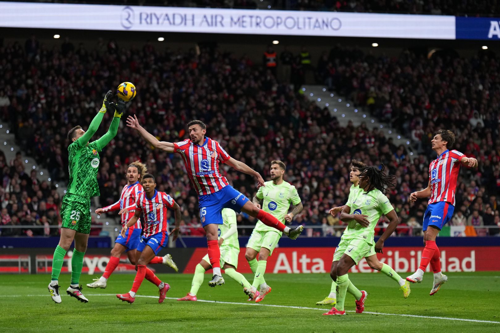 MADRID, SPAIN - MARCH 16: Wojciech Szczesny of FC Barcelona catches a ball under pressure from Clement Lenglet of Atletico de Madrid during the La Liga EA Sports match between Atletico de Madrid and FC Barcelona at Riyadh Air Metropolitano on March 16, 2025 in Madrid, Spain.