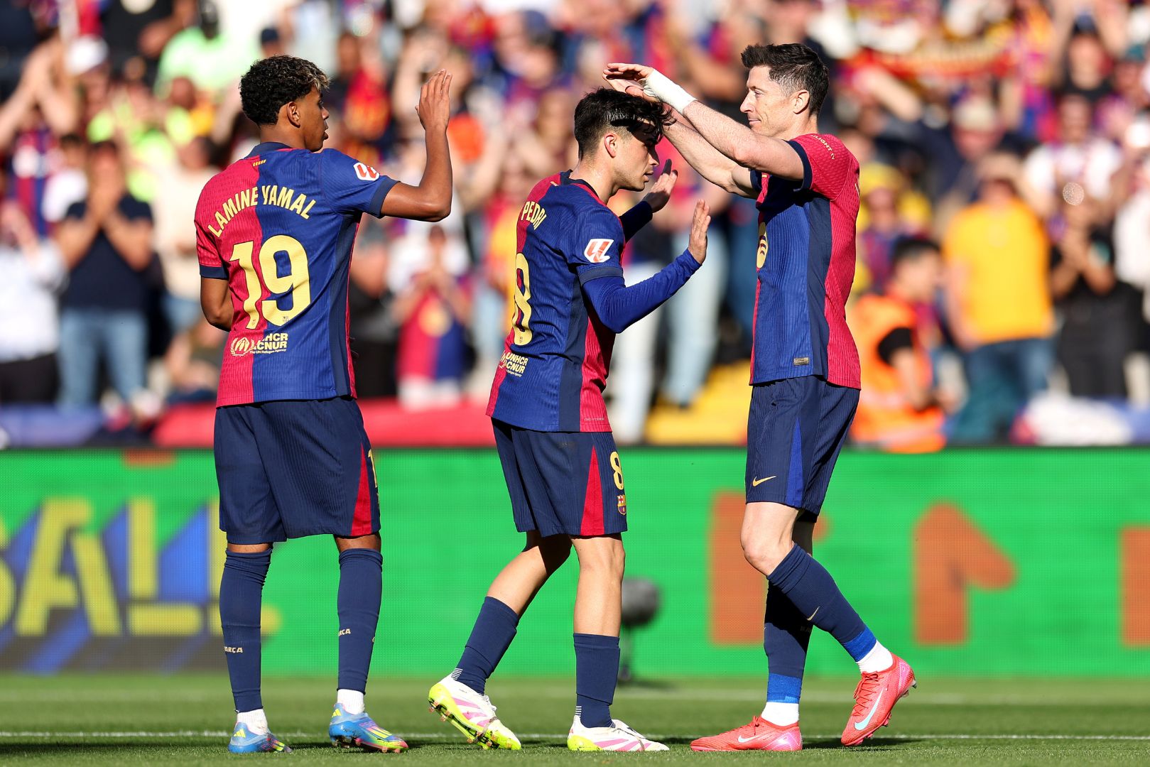 BARCELONA, SPAIN - MARCH 30: Robert Lewandowski of FC Barcelona (R) celebrates scoring his team's third goal with teammates Pedri and Lamine Yamal during the La Liga EA Sports match between FC Barcelona and Girona FC at Estadi Olimpic Lluis Companys on March 30, 2025 in Barcelona, Spain.
