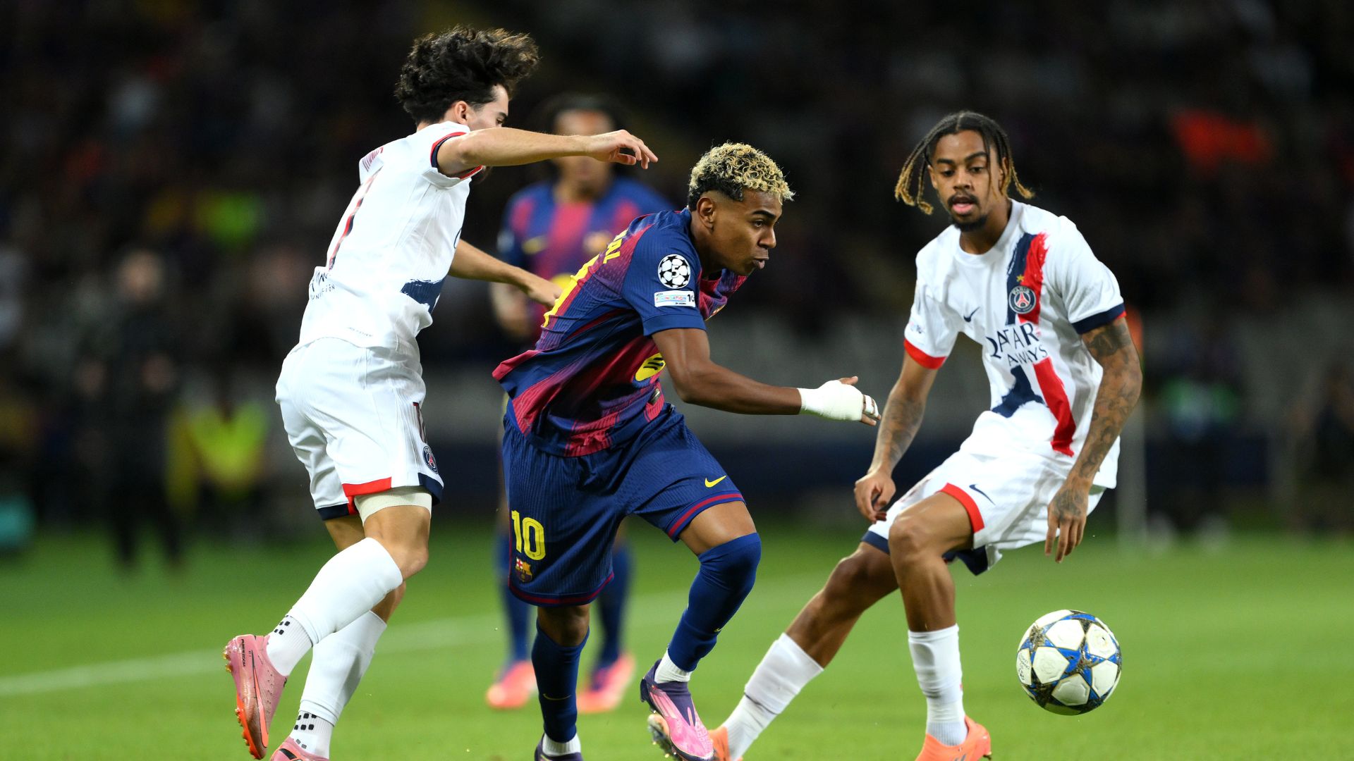 BARCELONA, SPAIN - OCTOBER 01: Lamine Yamal of FC Barcelona runs with the ball whilst under pressure from Vitinha and Bradley Barcola of Paris Saint-Germain during the UEFA Champions League 2025/26 League Phase MD2 match between FC Barcelona and Paris Saint-Germain at Estadi Olimpic Lluis Companys on October 01, 2025 in Barcelona, Spain.